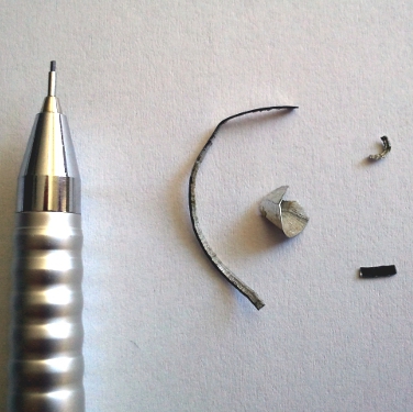 Metal chips/slivers and a pencil to demonstrate sliver sizes